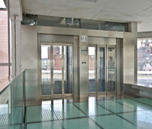 Frontal de un ascensor con acabado inoxidable y puertas de vidrio