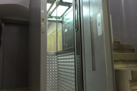 Puerta semiautomatica abierta de un ascensor pequeño en una comunidad de propietarios