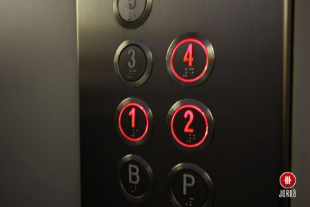 Pulsadores iluminados en rojo de una columna de botonera en cabina de ascensor