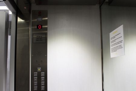 Interior de una cabina de ascensor reformado con medio espejo, techo inoxidable y botonera