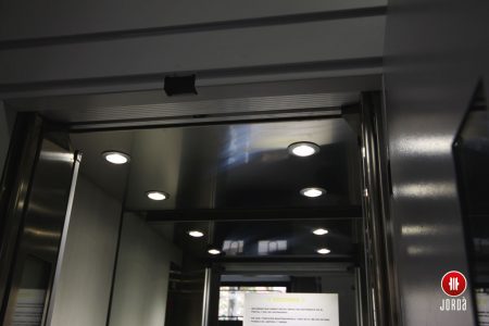 Interior de una cabina de ascensor con techo inoxidable y iluminación de led