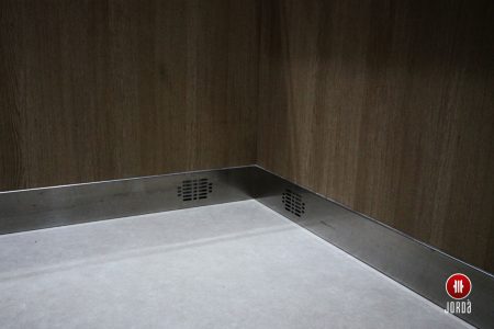 Zócalo de inoxidable y pare de formica en el interior de una cabina de ascensor